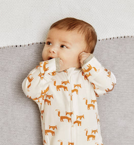 Baby lying on an organic cotton knitted baby blanket from Kit & Kin